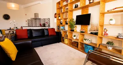 a living room with a black couch and a tv at Casa do Recanto - Loft vista rio in Porto