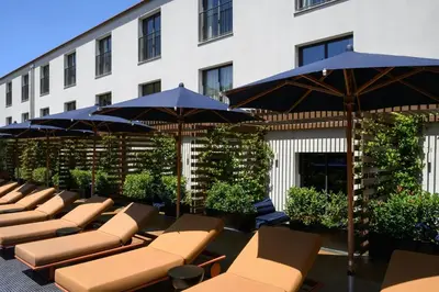 a row of lounge chairs and umbrellas in front of a building at Forte de Gaia, Autograph Collection in Vila Nova de Gaia