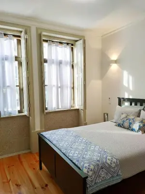 a bedroom with a large bed with two windows at Porto Historic - Apartment with Private Patio in Porto
