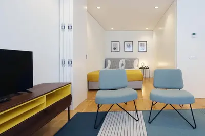 a bedroom with a bed and two chairs and a tv at HM - Sta. Catarina Charming Apartment in Porto