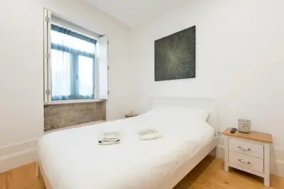 a white bedroom with a white bed and a window at Warmly Porto in Porto