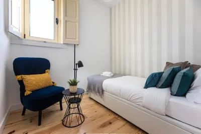 a bedroom with a bed and a blue chair at Vila Burgães by LovelyStay in Porto