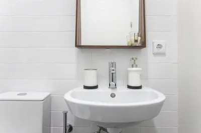 a white bathroom with a sink and a mirror at Vila Burgães by LovelyStay in Porto