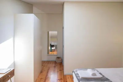 a bedroom with white walls and a bed with a mirror at History Porto in Porto
