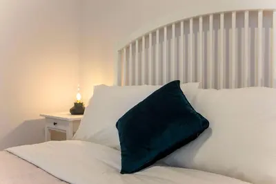 a white bed with a green pillow on it at LovelyStay - 2BR Flat with AC in Duque de Loulé in Porto