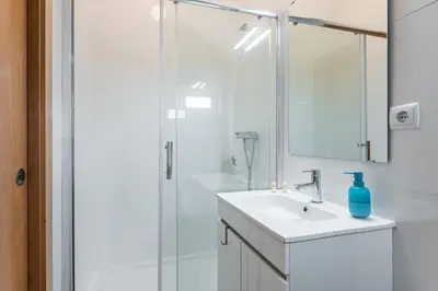a white bathroom with a sink and a shower at GuestReady - Yazdah Flat 3 in Porto