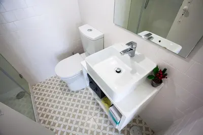 a white bathroom with a sink and a toilet at Oporto City View - Flora Garden in Porto