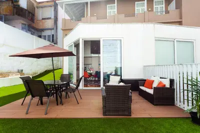 a patio with a table and chairs and an umbrella at Oporto City View - Flora Garden in Porto