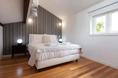 a white bedroom with a bed and a window at TMH Torrinha in Porto