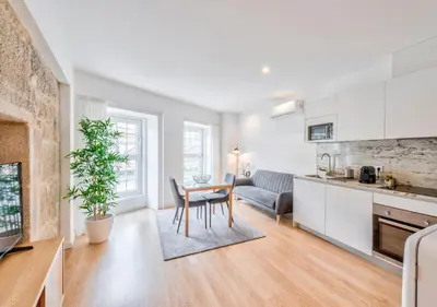 a kitchen and living room with a table and a couch at Oporto Comfort Dom Hugo - Historic Apartments in Porto