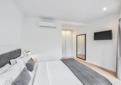 a white bedroom with a large bed and a flat screen tv at Oporto Comfort Dom Hugo - Historic Apartments in Porto