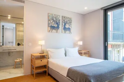 a bedroom with a bed and a bathroom at LovelyStay - Primrose 2BR Flat with Free Parking, AC and Balcony in Porto