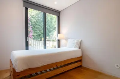 a bedroom with a bed and a large window at LovelyStay - Primrose 2BR Flat with Free Parking, AC and Balcony in Porto