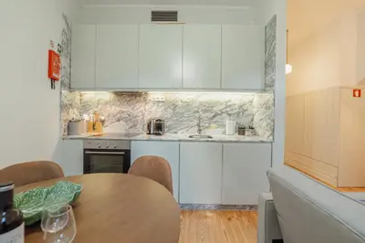a kitchen with white cabinets and a wooden table at Cozy Flat with Terrace by Hosty in Porto