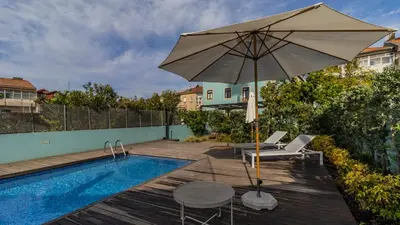 a patio with an umbrella and chairs and a pool at LovelyStay - Downtown Studio with Pool, AC and Balcony in Porto
