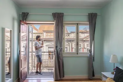 a man standing on a balcony looking out of a window at Host Wise - Colorful Bright Flat with Balcony in Porto