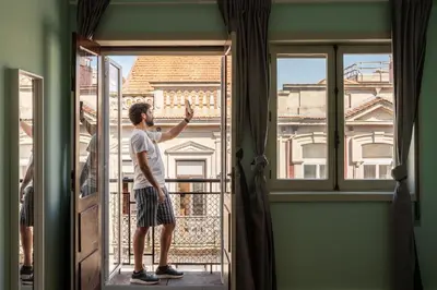 a man is looking out of a window at Host Wise - Colorful Bright Flat with Balcony in Porto