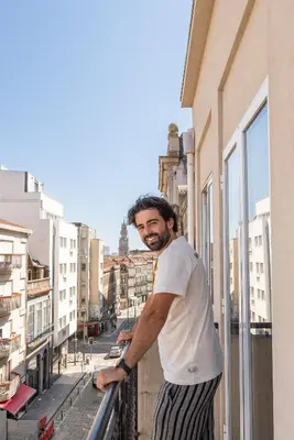 a man standing on a balcony looking out of a window at Host Wise - Colorful Bright Flat with Balcony in Porto