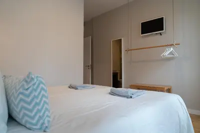 a bedroom with a white bed with a tv on the wall at Clerigos Townhouse Porto by PCH in Porto