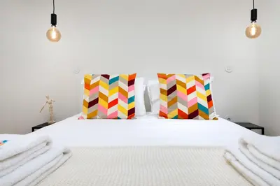 a bedroom with a white bed with colorful pillows at Liiiving in Porto - Santa Catarina Boutique in Porto