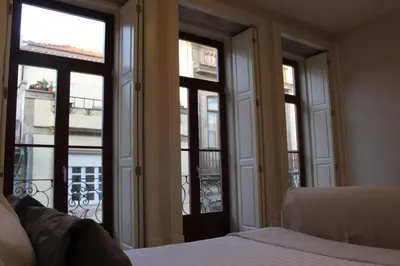 a bedroom with three windows and a bed and a balcony at Oporto Coliseum Studio in Porto