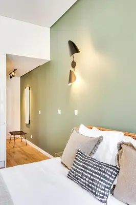 a bedroom with a white bed with a lamp on the wall at DA'HOME - Boavista Green Studio in Porto