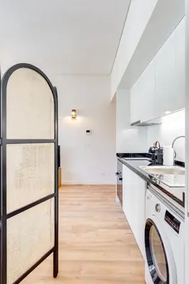 a kitchen with white cabinets and a washer and dryer at DA'HOME - Boavista Green Studio in Porto