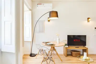 a living room with a table and a floor lamp at DA'HOME - Boavista Green Studio in Porto