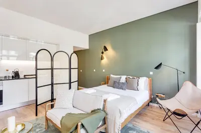 a bedroom with a bed and two chairs at DA'HOME - Boavista Green Studio in Porto