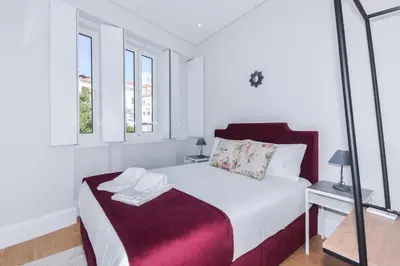 a white bedroom with a bed and two windows at Fontinha Square Apartments by Porto City Hosts in Porto