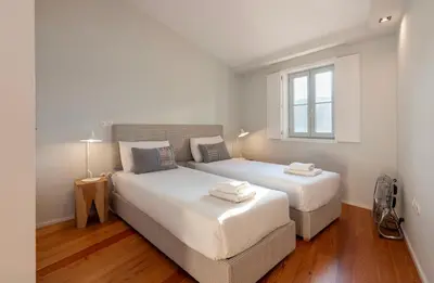 two beds in a white room with a window at Duplex Douro River in Porto