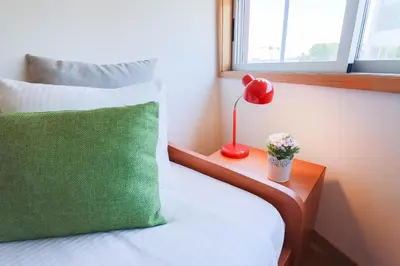 a bed with a green pillow and a lamp on a table at Porto Cathedral II in Porto