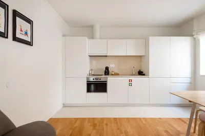 a white kitchen with white cabinets and a wooden floor at Bombarda Homes in Porto