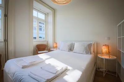 a bedroom with a white bed with towels on it at Solar Studio Fontainhas in Porto