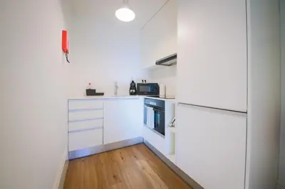 a kitchen with white cabinets and a refrigerator at Solar Studio Fontainhas in Porto