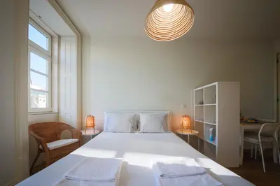 a bedroom with a large white bed with two towels on it at Solar Studio Fontainhas in Porto