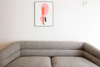 a grey couch with a pink picture on the wall at Cedofeita Studio 176 - Studio in city center in Porto