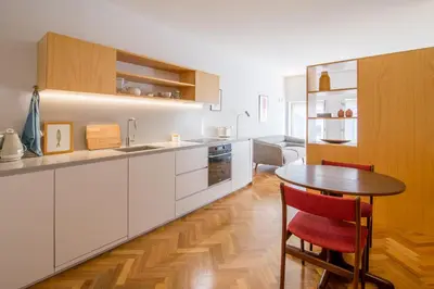a kitchen with white cabinets and a wooden table at Cedofeita Studio 176 - Studio in city center in Porto
