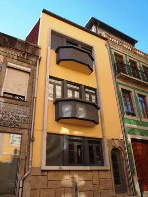 a yellow building with black windows on a street at 107 Rosario, Guesthouse in Porto