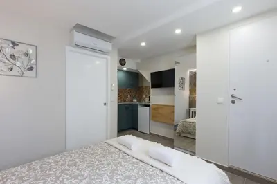 a white bedroom with a bed and a kitchen at OportoHost Cozy Studios in Porto