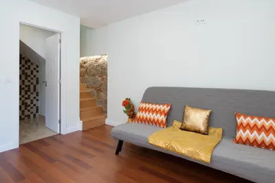 a living room with a gray couch with orange pillows at OportoHost Dragão Duplex in Porto
