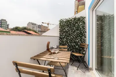 a wooden table with wine glasses on a balcony at OportoHost Campanhã in Porto