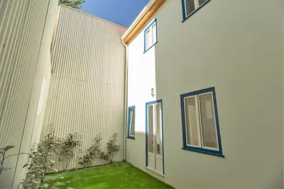 a white building with blue windows and green grass at Janelas de São Bento 3 by Porto City Hosts in Porto