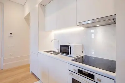 a white kitchen with a microwave and a sink at BOUTIQUE Rentals- Art & Charm Apt w/ balcony & garage in Porto