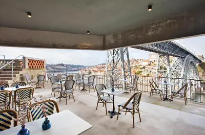 a balcony with tables and chairs and a view of a city at Vincci Ponte de Ferro in Vila Nova de Gaia