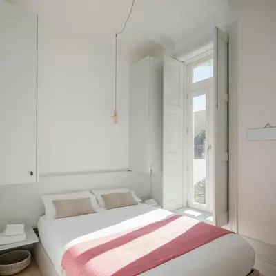 a white bedroom with a bed and a window at Charming Camões Apartment in Porto with AC & Wi-Fi in Porto