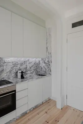 a kitchen with white cabinets and marble counter tops at Charming Camões Apartment in Porto with AC & Wi-Fi in Porto