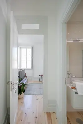 a white bathroom with a sink and a mirror at Charming Camões Apartment in Porto with AC & Wi-Fi in Porto