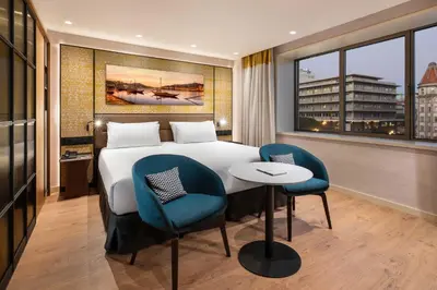 a hotel room with a bed and two chairs and a table at Eurostars Aliados in Porto
