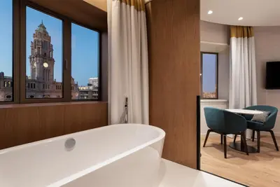 a bathroom with a tub and a table and a clock tower at Eurostars Aliados in Porto
